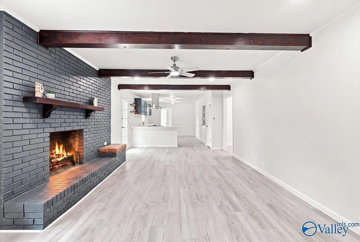 Family room with exposed wood ceiling beams, a brick fireplace, and wood-look plank flooring
