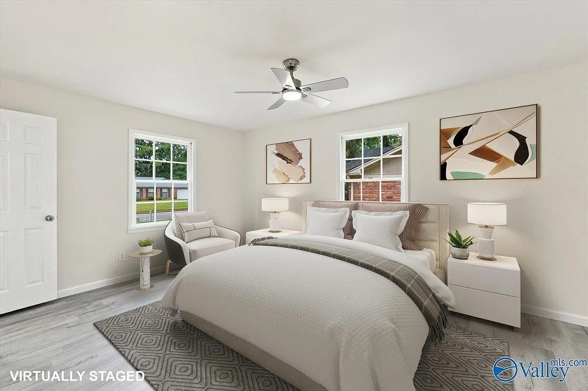 Primary bedroom with a neutral palette, wood-look flooring, and natural daylight