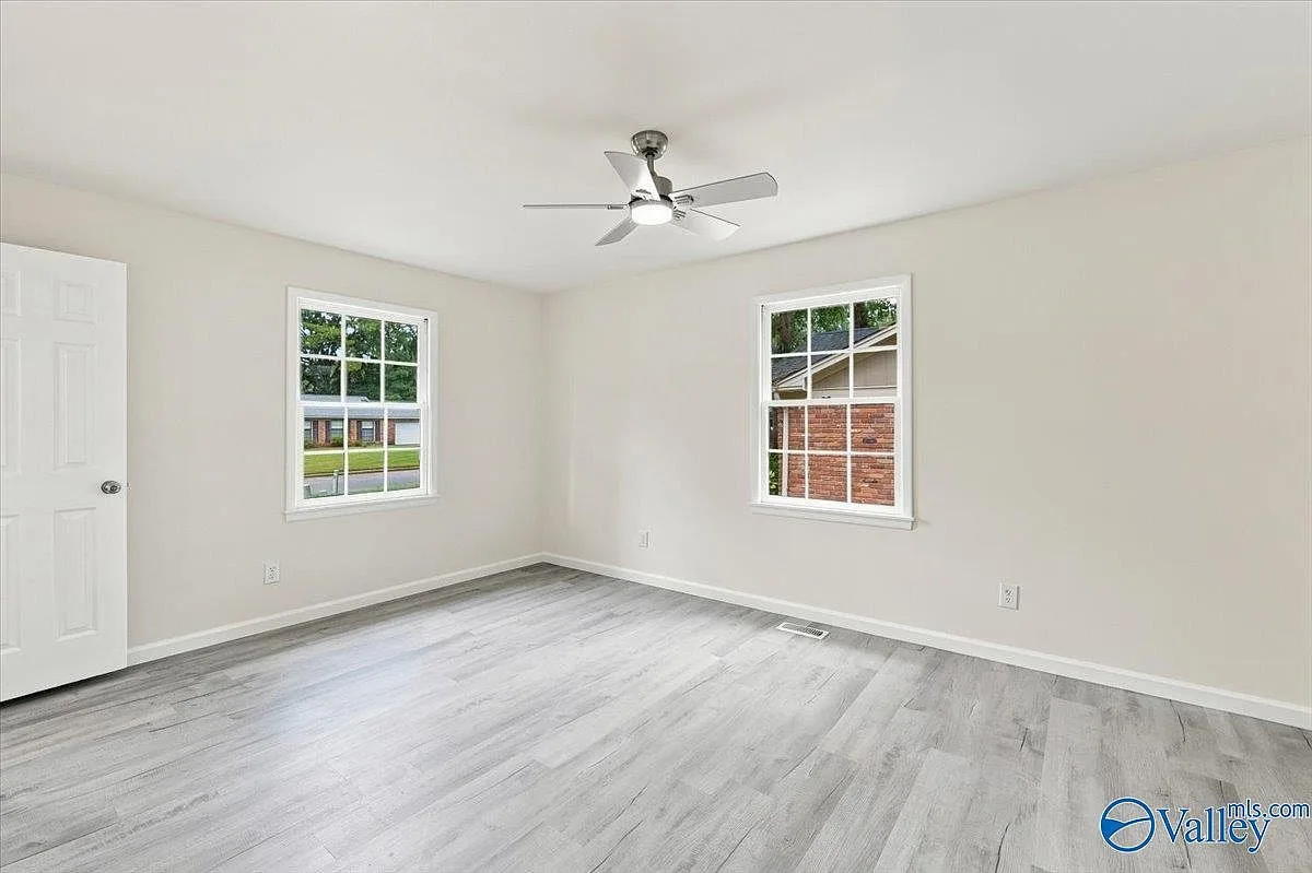 Bright secondary bedroom with two windows and plank flooring