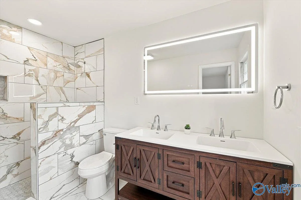 Primary bath with a large walk-in tiled shower and dark wood double-sink vanity