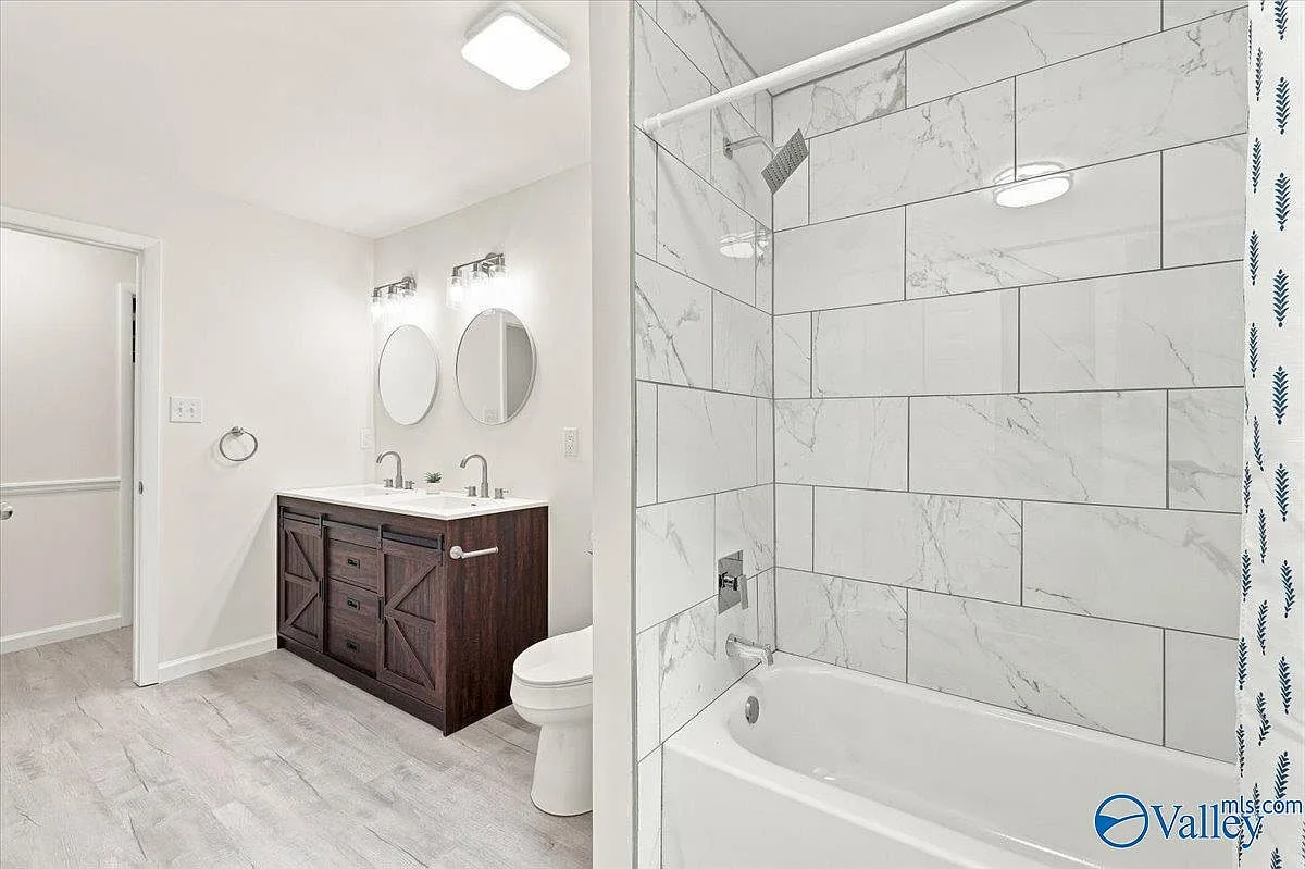 Bathroom with a barn-door vanity, circular mirrors, and white subway tile tub surround