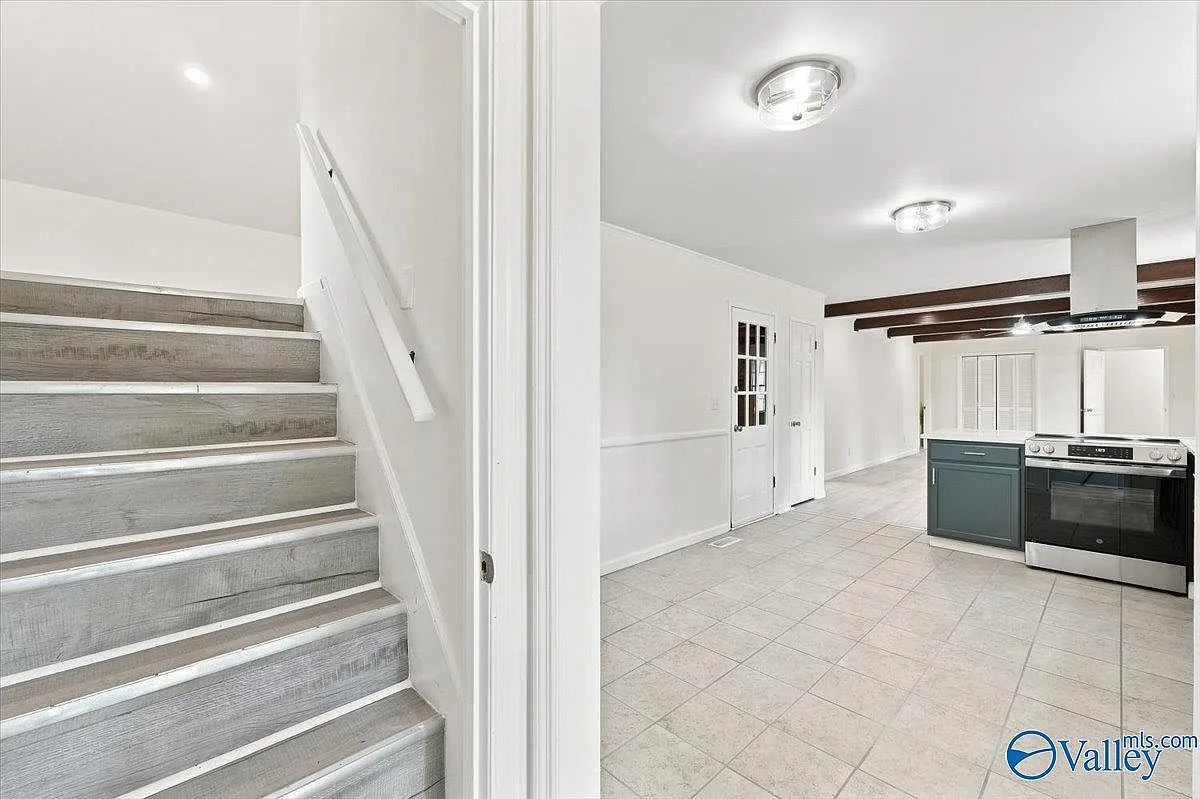 View from the staircase down toward the kitchen with exposed beams