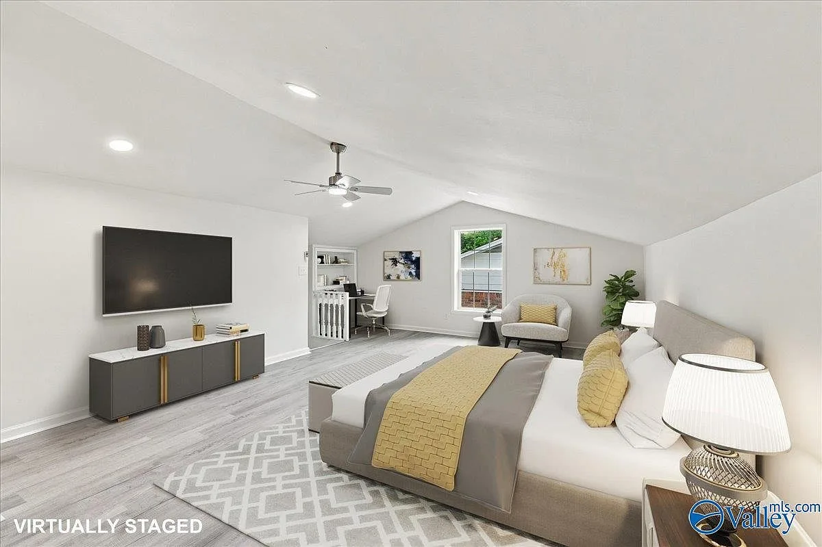 Primary bedroom with a vaulted ceiling, wood-look flooring, and bright natural light