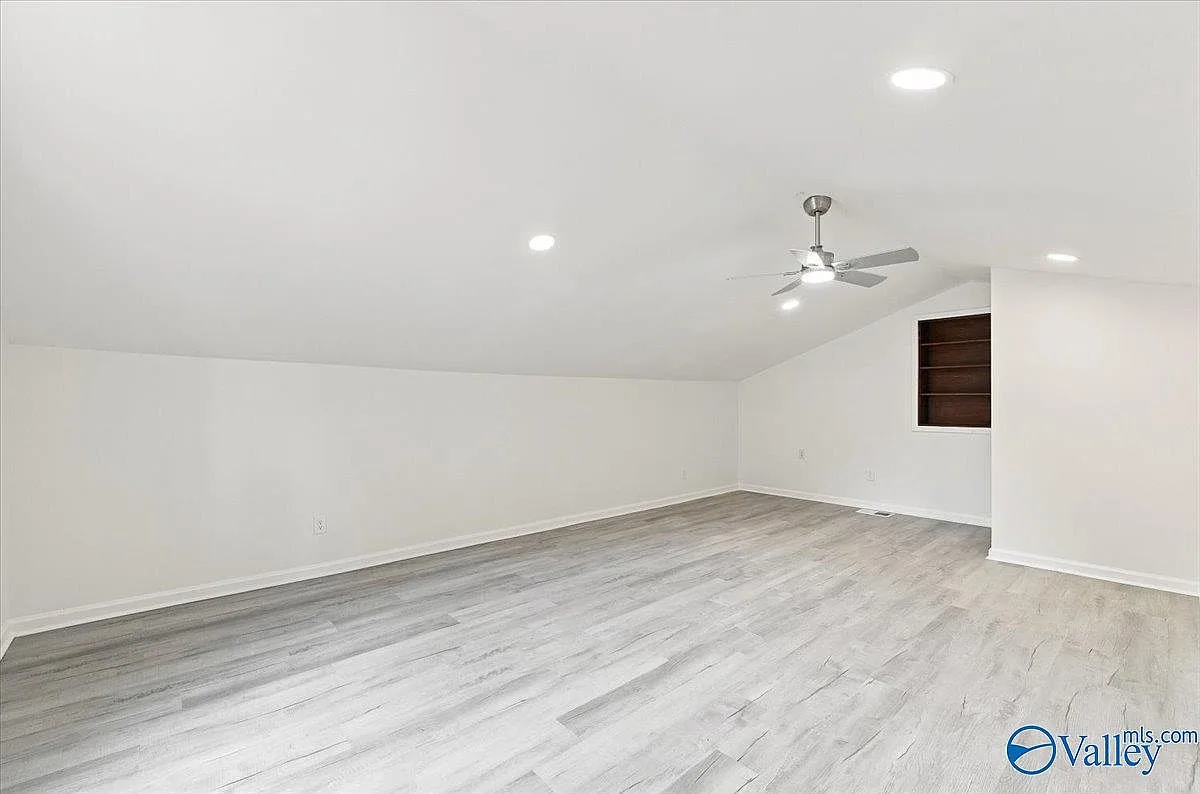 Large room with a sloped ceiling and a built-in shelving nook