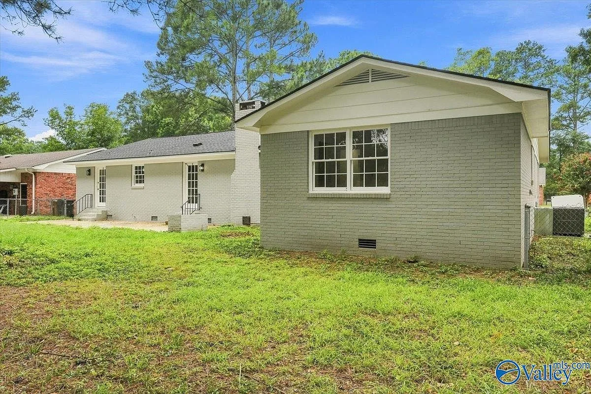 Large concrete patio behind the house with a fenced lawn and clear sky