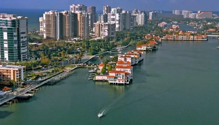 Aerial view of Bonita Springs waterfront homes, boats, and the coastal skyline in the distance