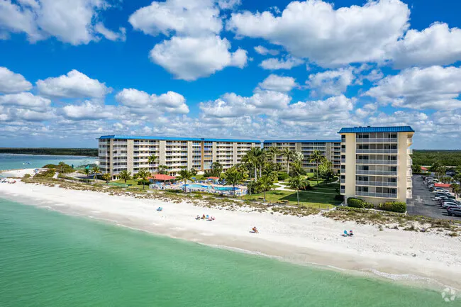 Drone aerial of a beachfront condominium complex on Bonita Beach with pool and white sand