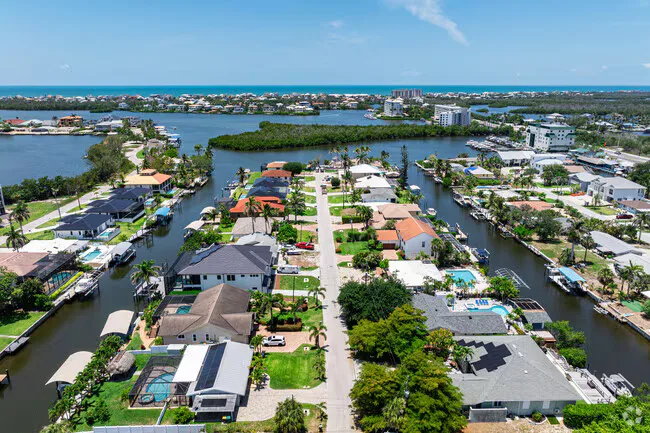 Drone aerial of a Bonita Springs waterfront neighborhood with canal-front homes, docks, and pools