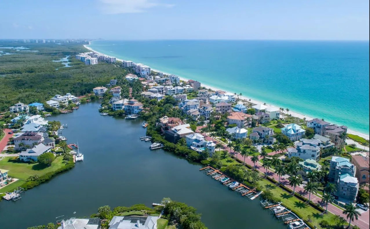 Aerial view of a Naples waterfront community with homes, private docks, and boats moored along the canals