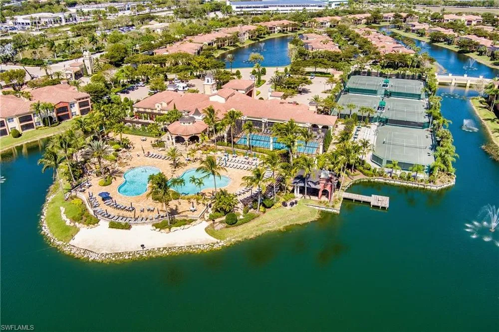 Aerial view of Estero community amenities with pools, tennis courts, and lakefront landscaping