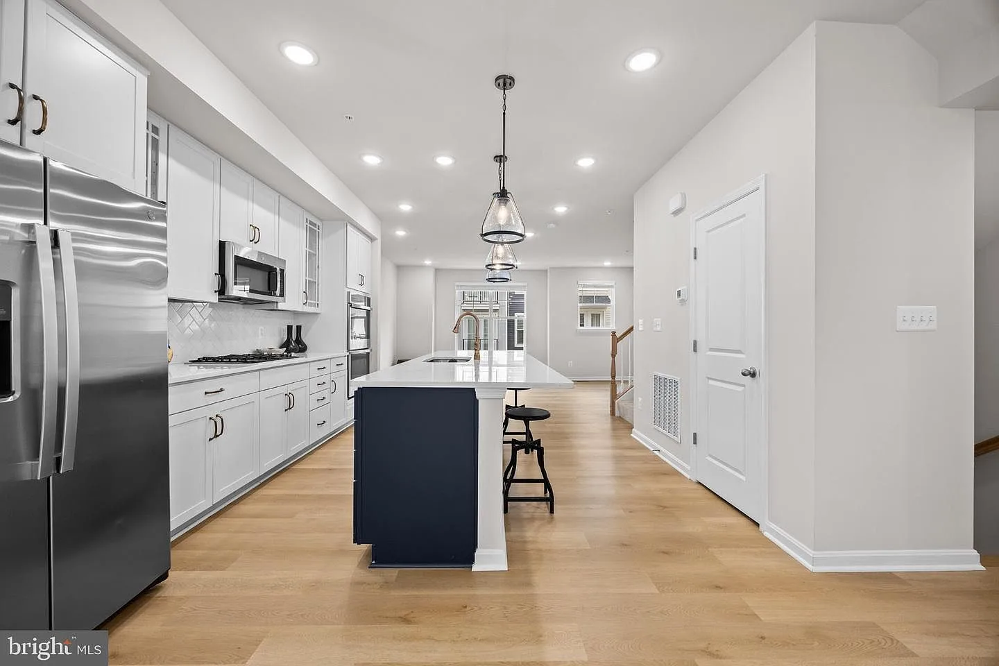 Modern kitchen with white shaker cabinets and a dark blue island