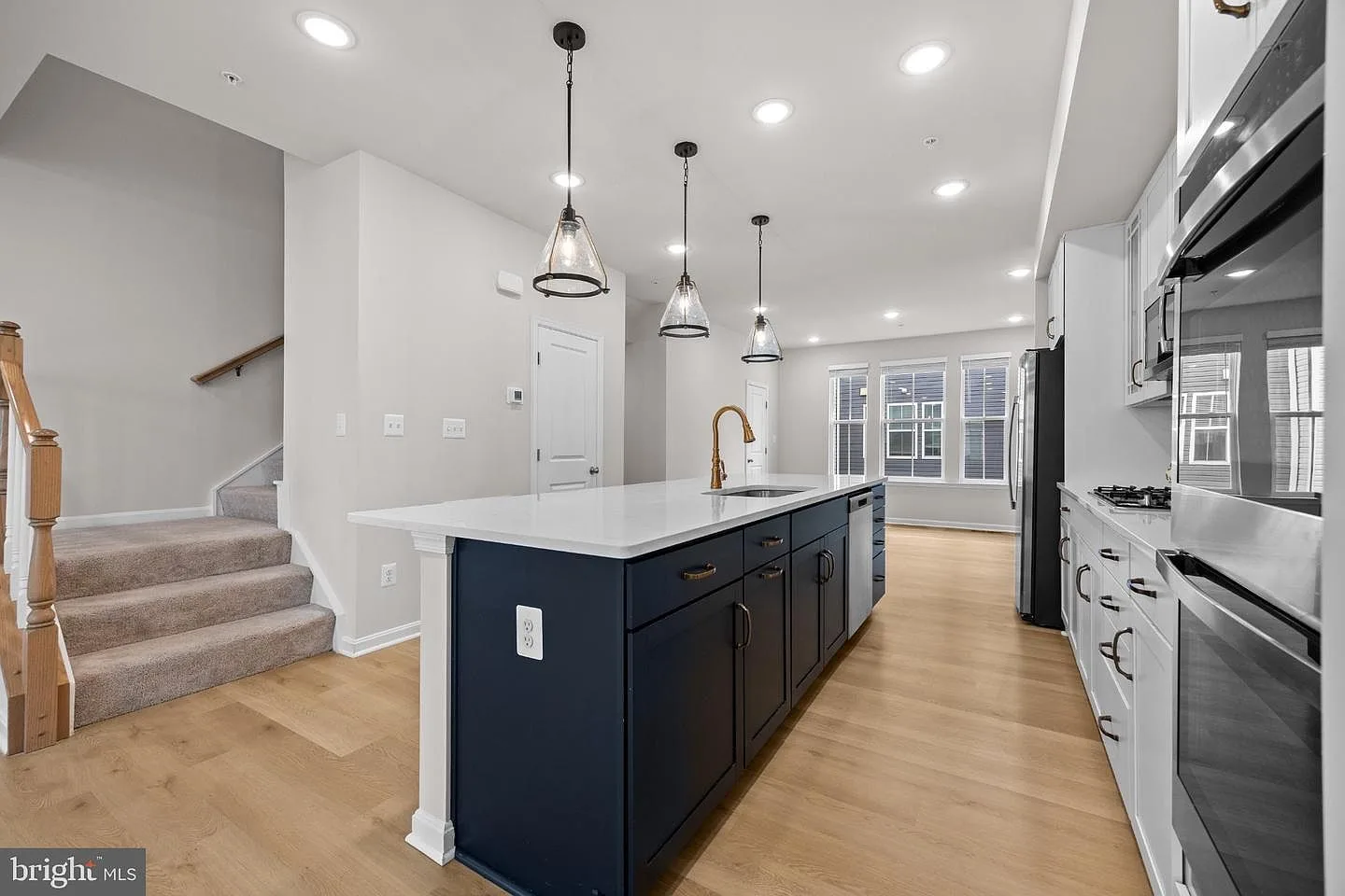 Navy kitchen island with quartz countertop, pendant lights, and white cabinetry