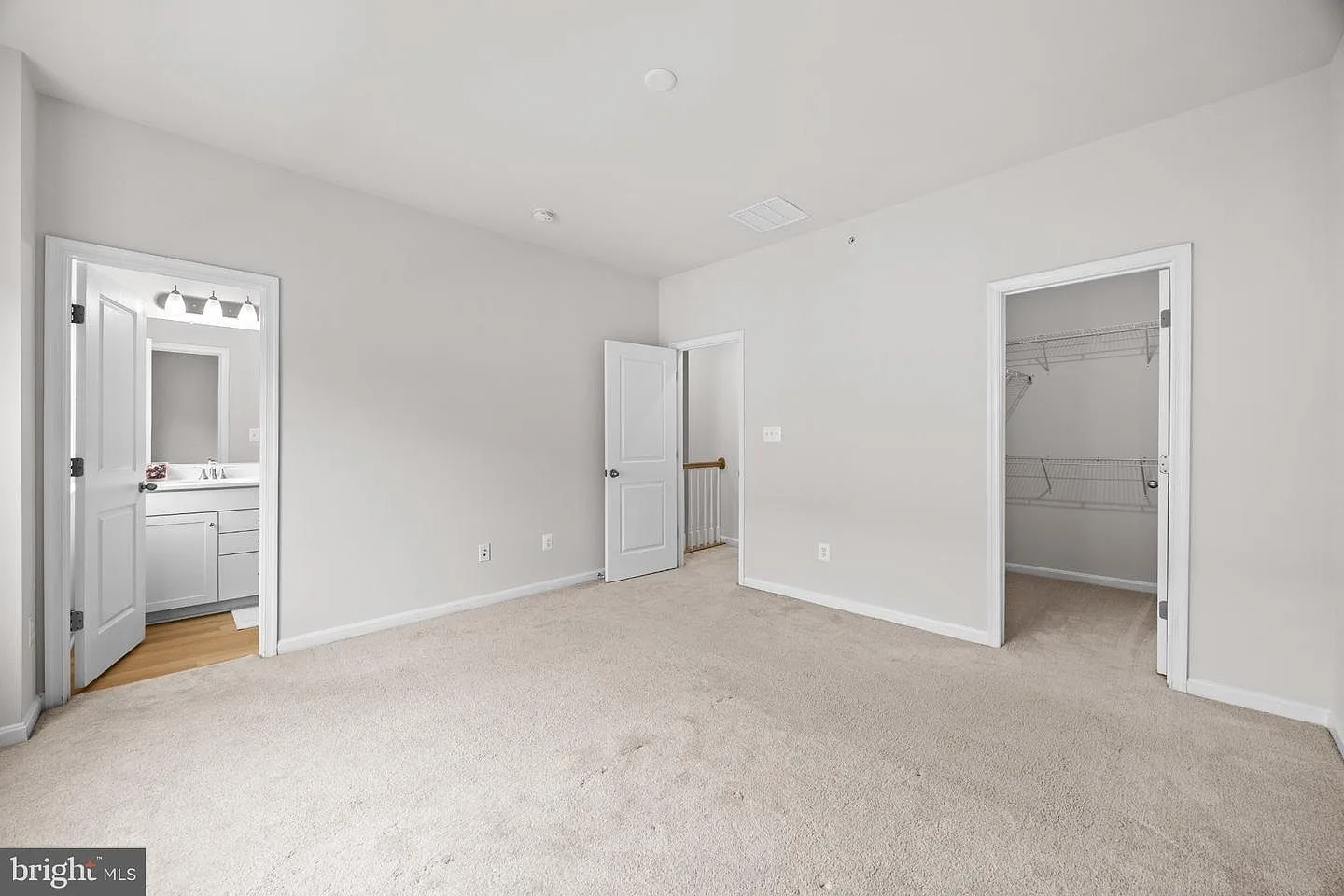 Primary suite with carpet, large window, and en-suite bath beyond