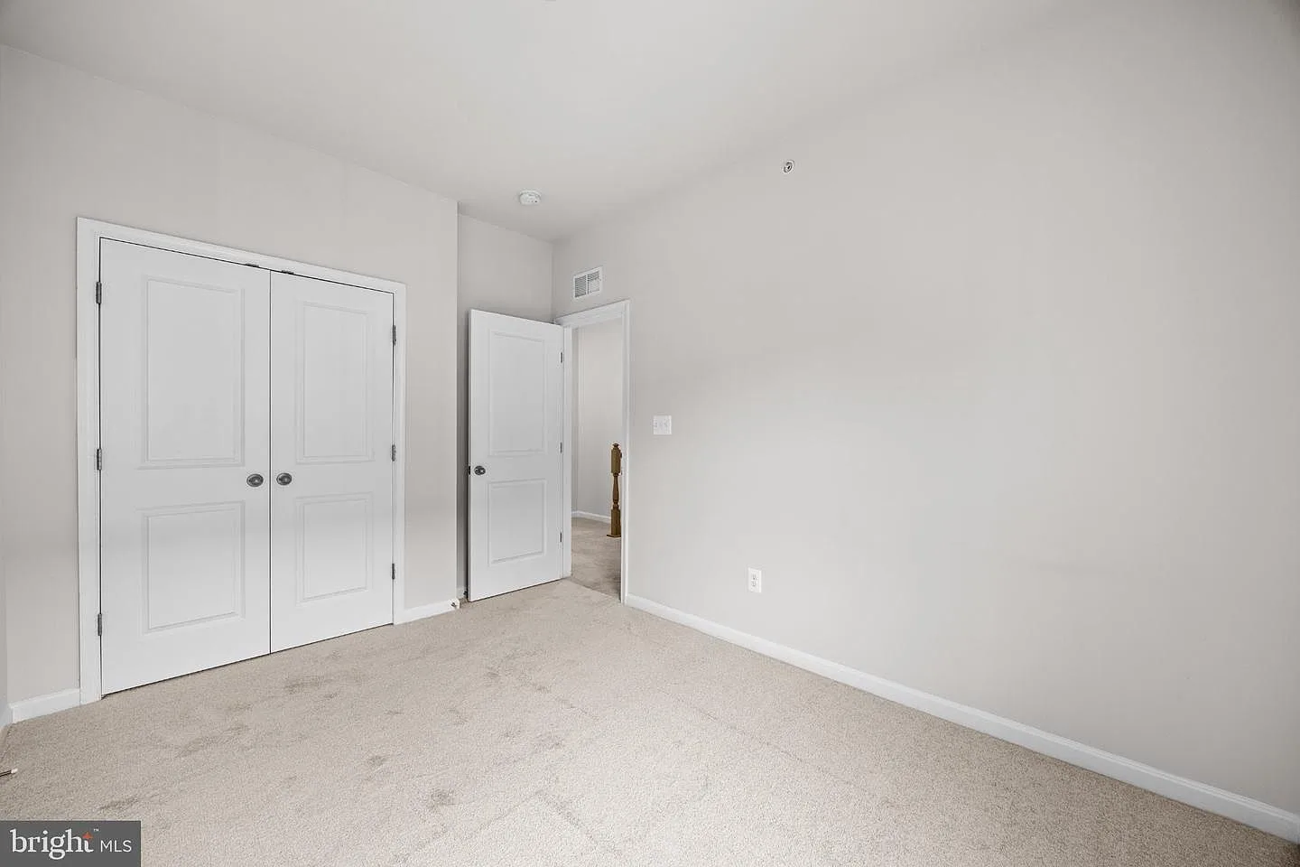 Bedroom with double-door closet and hallway beyond
