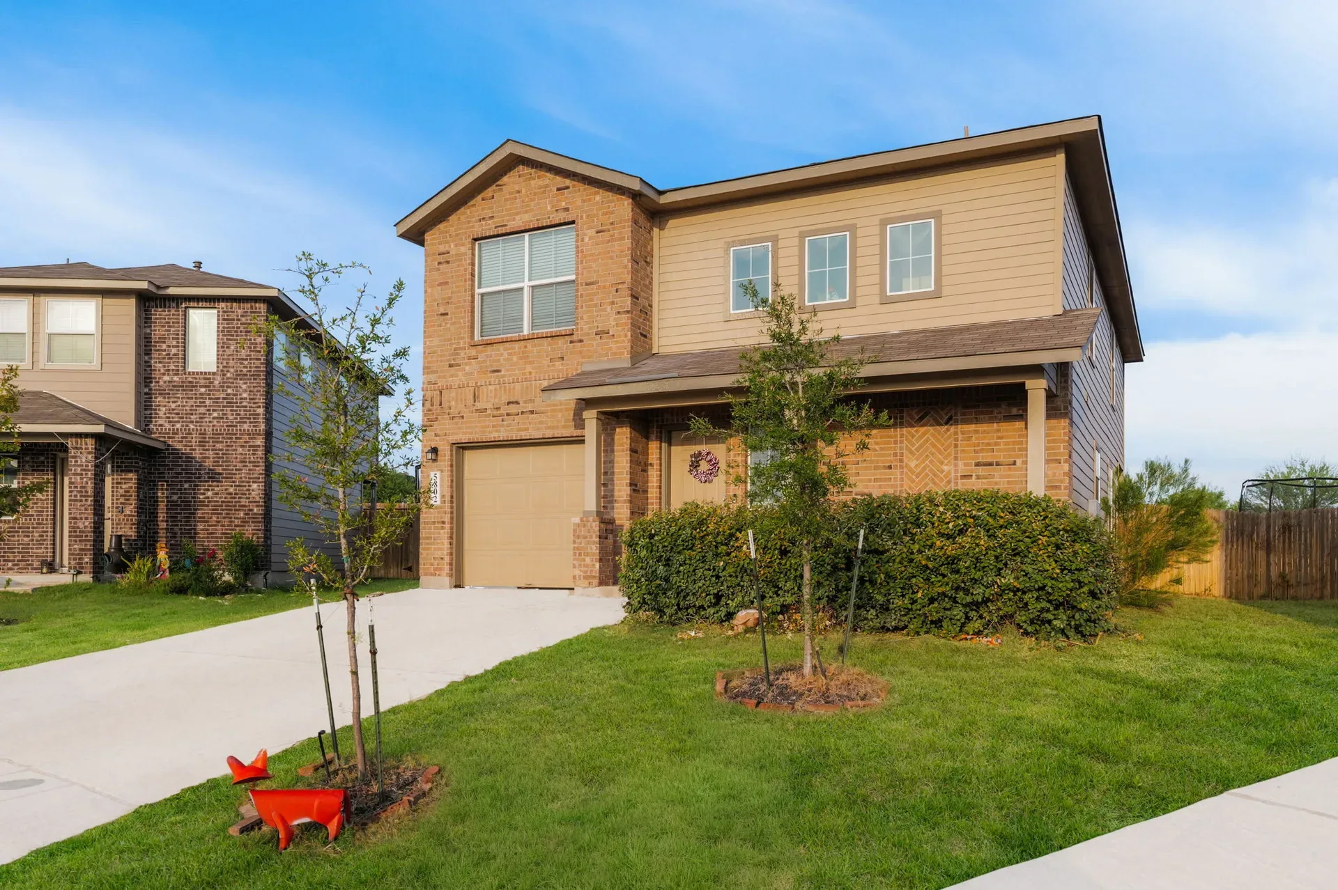 Two-story brick facade of the home with a tidy front lawn and driveway