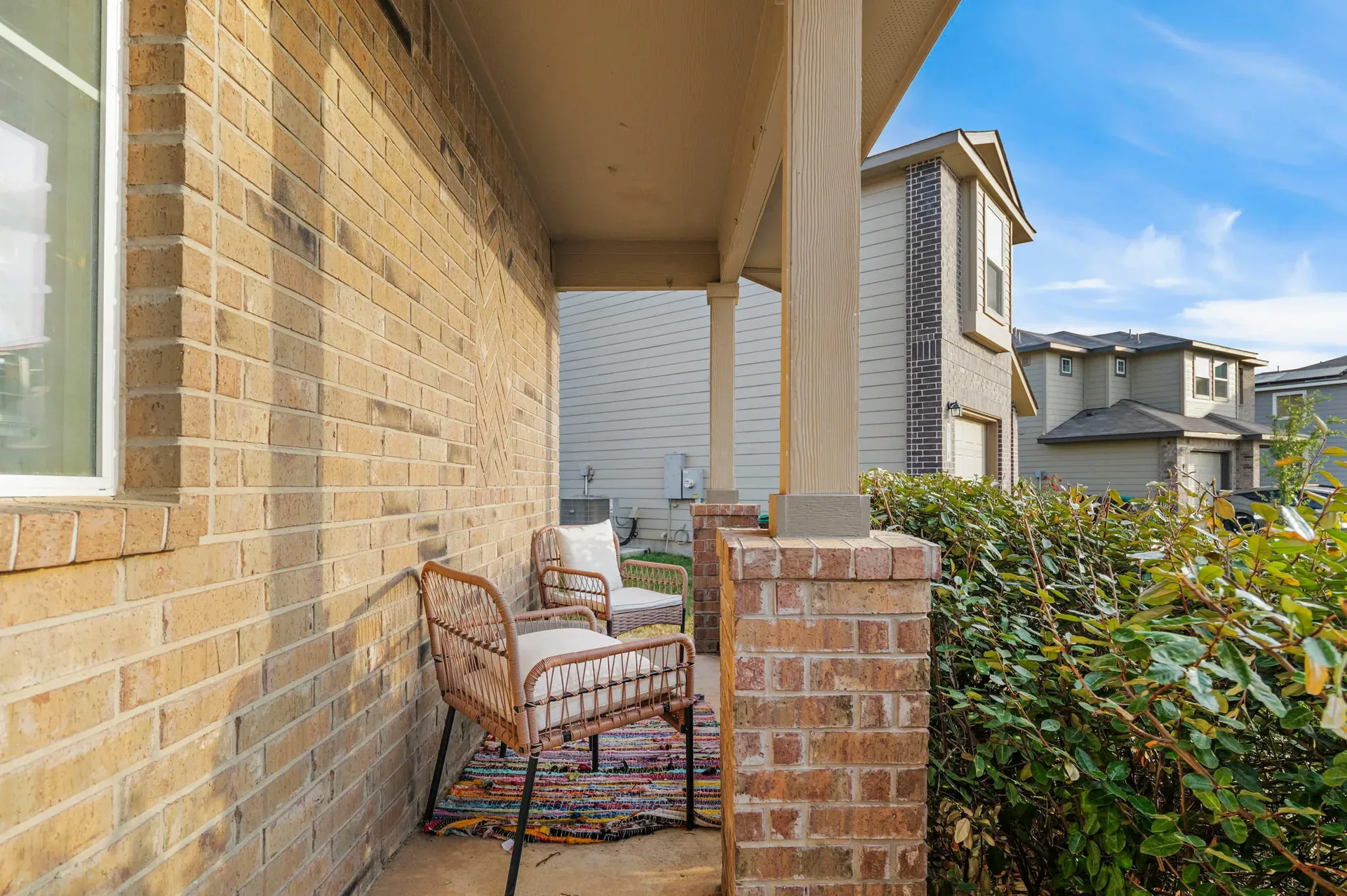 Covered front porch with tan brick veneer and wood support columns