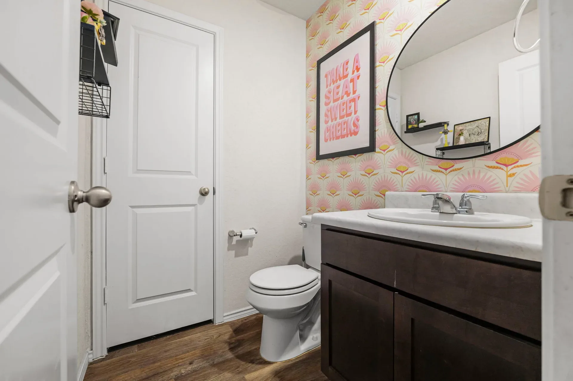 Powder room with dark wood vanity, white countertop, and oval mirror