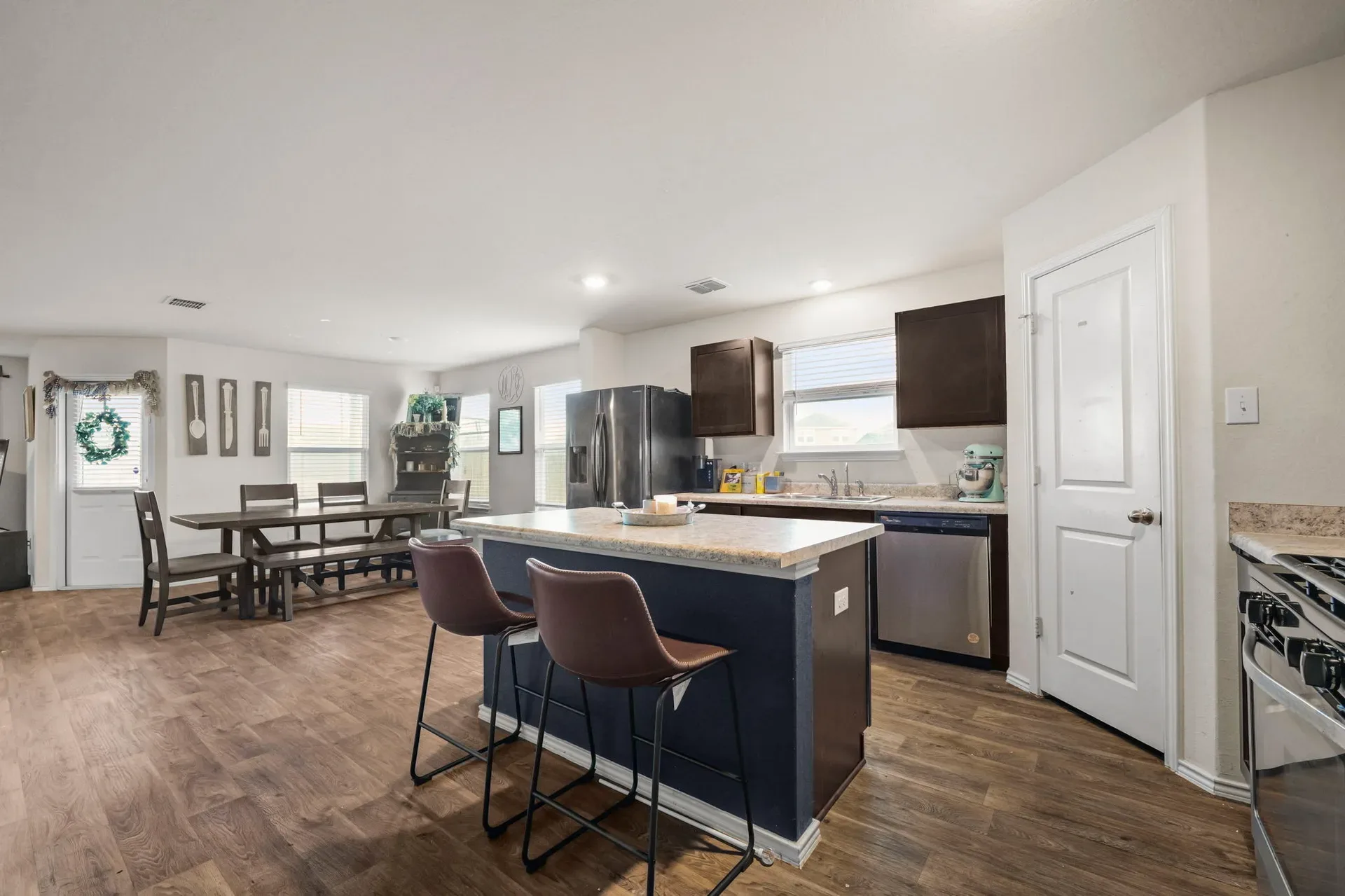 Open-plan kitchen and dining area with dark blue island and wood-look flooring