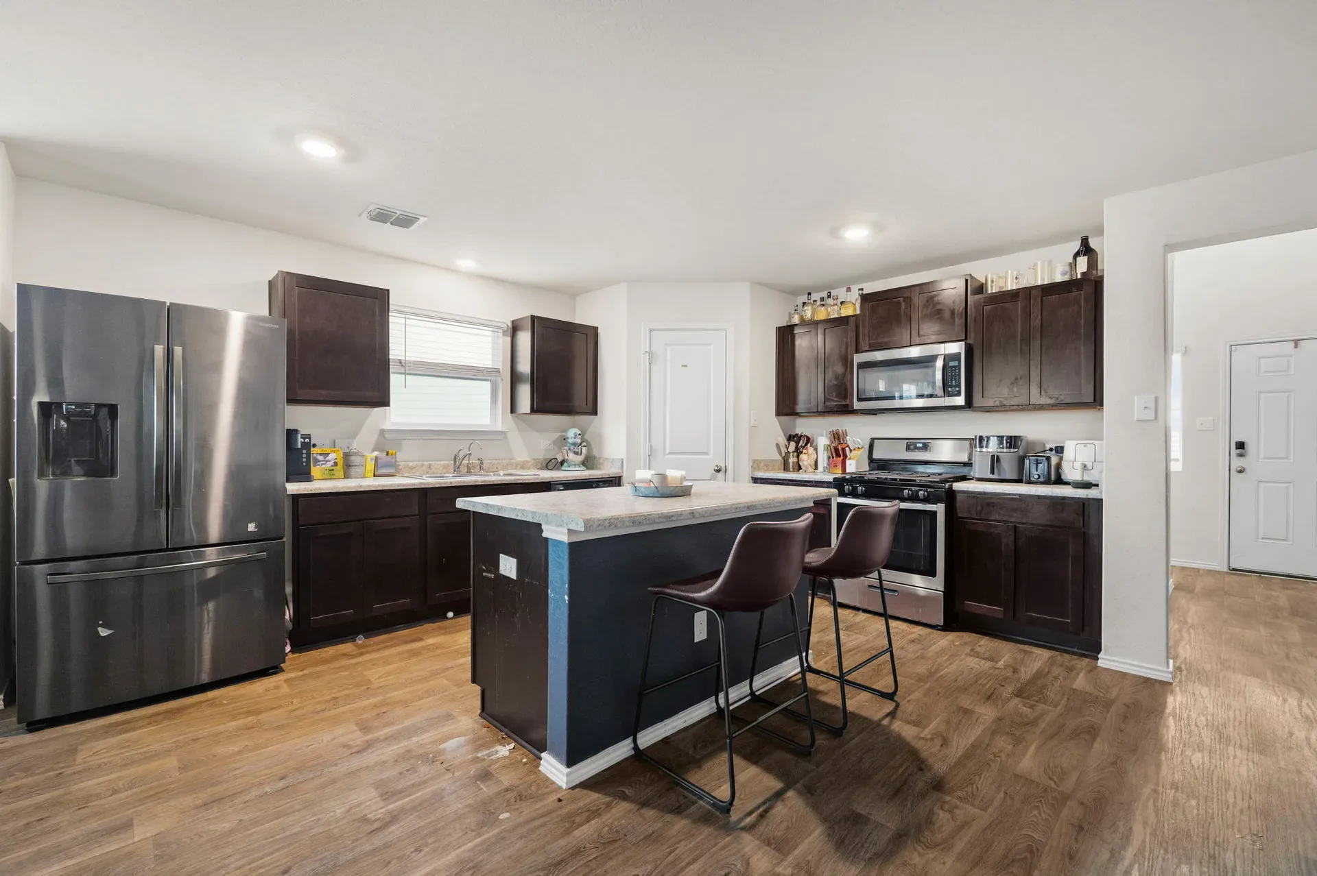 Kitchen with dark espresso cabinetry, island with blue base, and stainless appliances