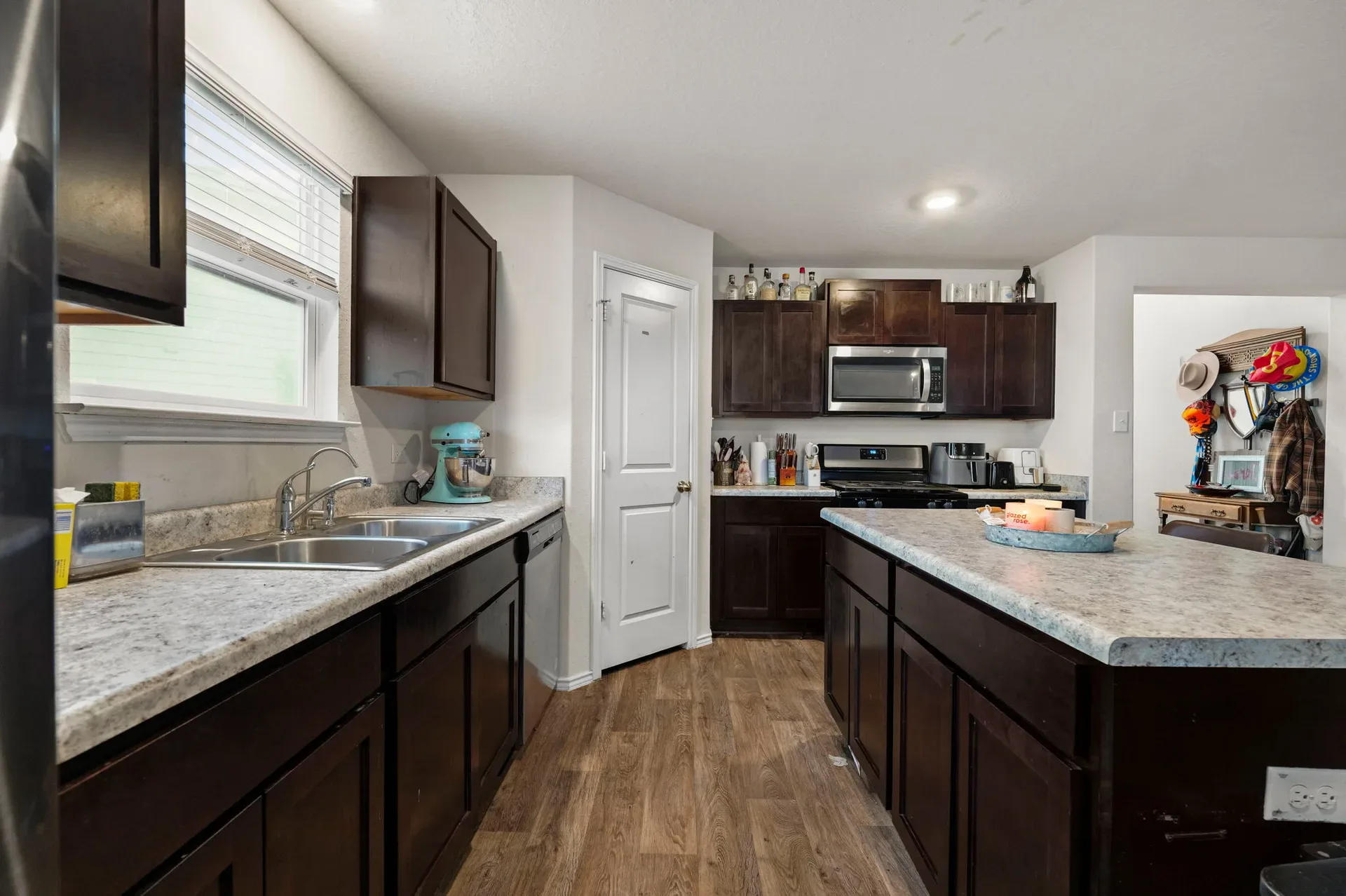 Wide view of the kitchen with dark cabinetry and light countertops