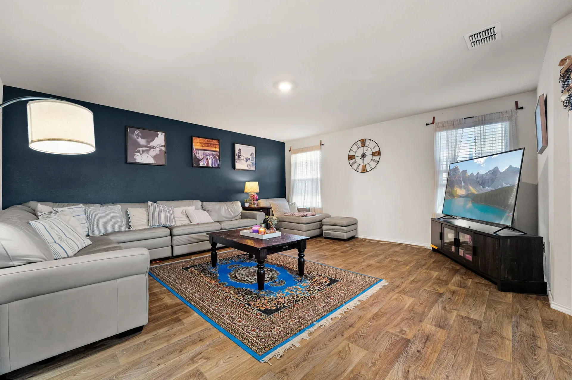 Living room with a navy blue accent wall and wood-look flooring