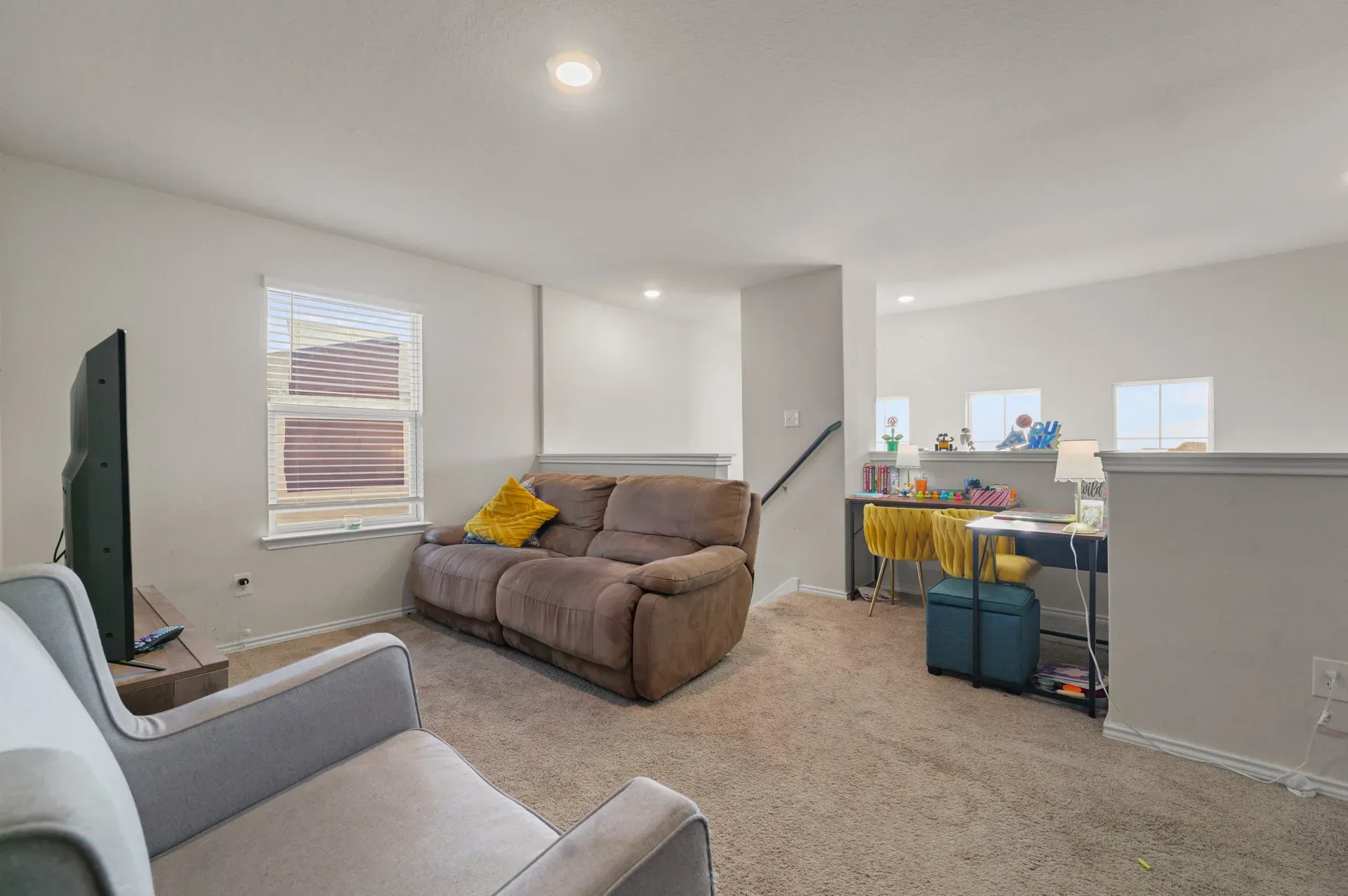 Upstairs loft living area with carpeted flooring and recessed lighting