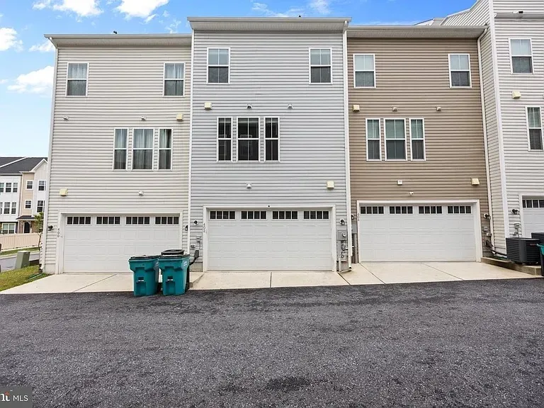 Rear exterior with two-car garage doors and concrete driveway