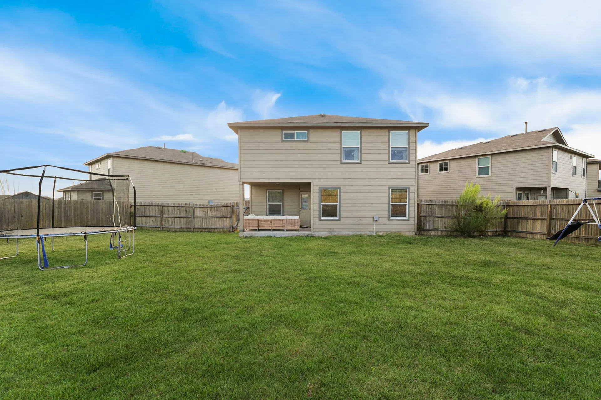 Rear view of the two-story home with lawn and wood privacy fencing