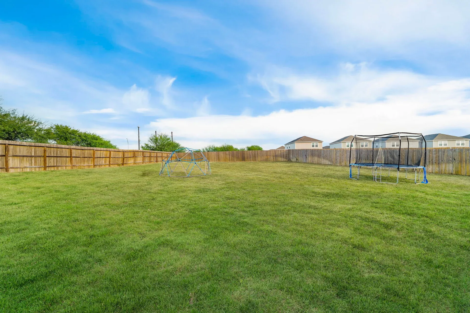 Spacious grassy backyard enclosed by wood privacy fencing