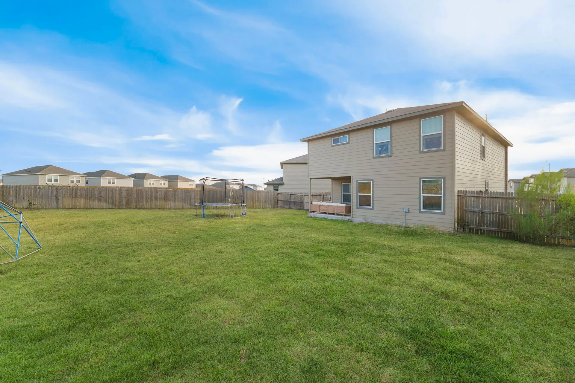 Backyard view of the home with siding and privacy fencing in sunlight