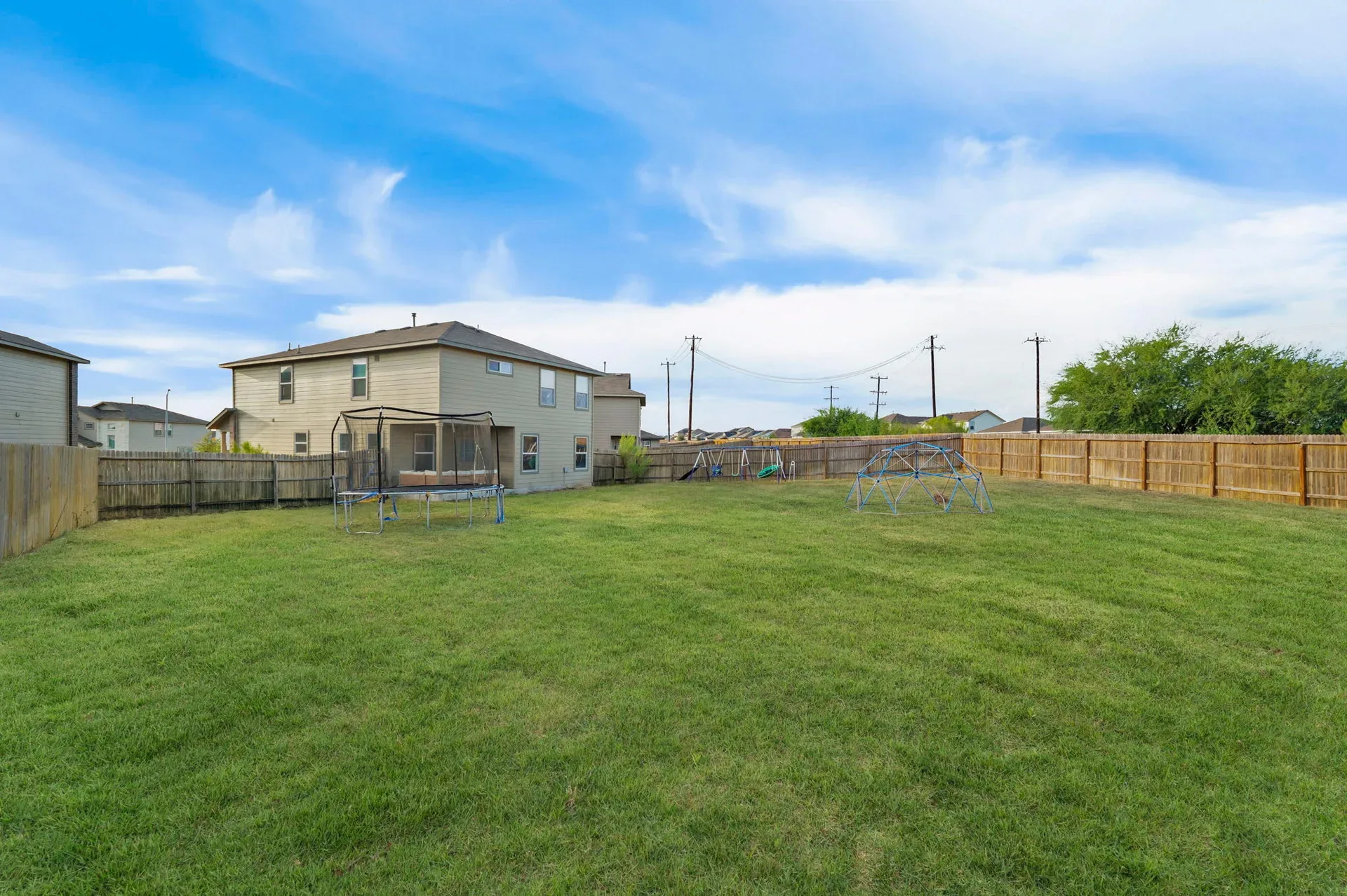 Wide view of the large backyard lawn behind the two-story home