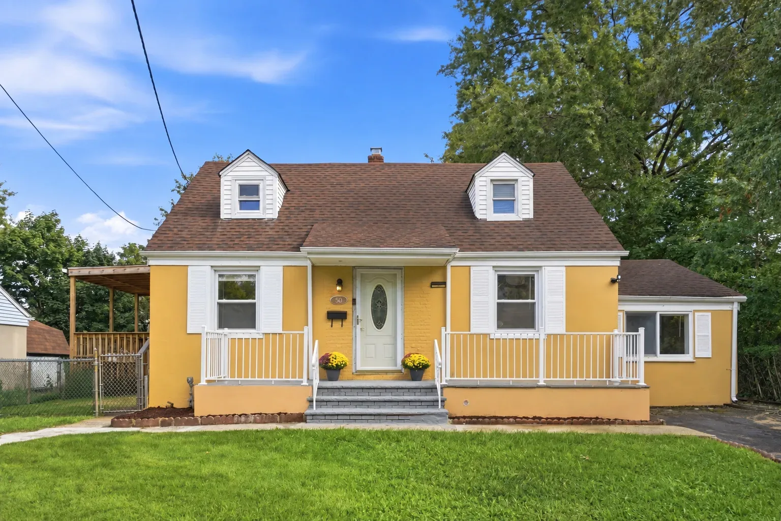 Yellow Cape Cod home at 50 Heather Lane in Roselle, NJ with white shutters, dormer windows, and a front porch