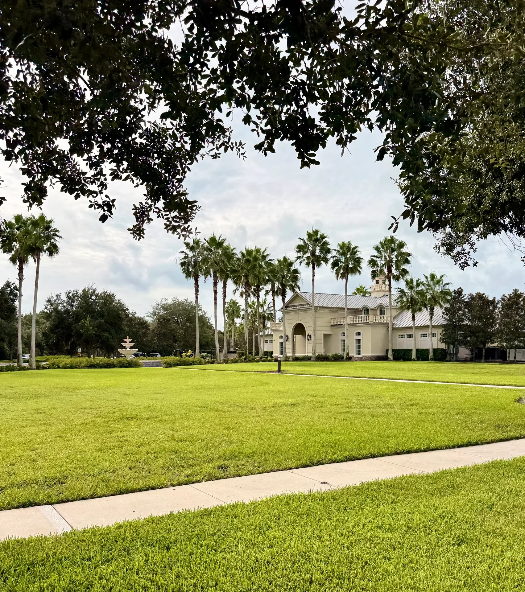 The Coastal Oaks community amenity center on manicured grounds with tall palm trees and a fountain
