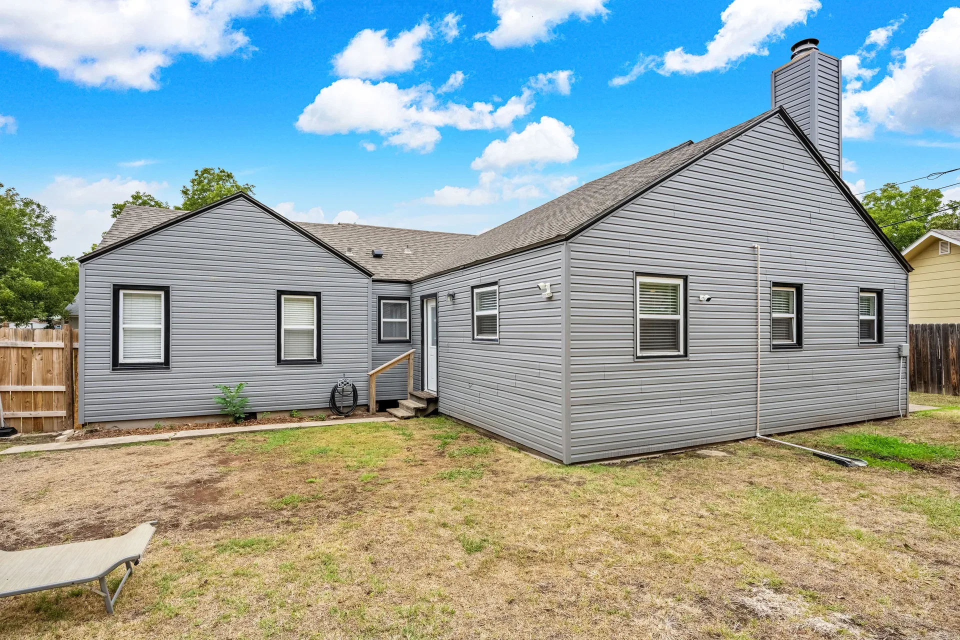Backyard exterior of the home with gray siding and black window trim