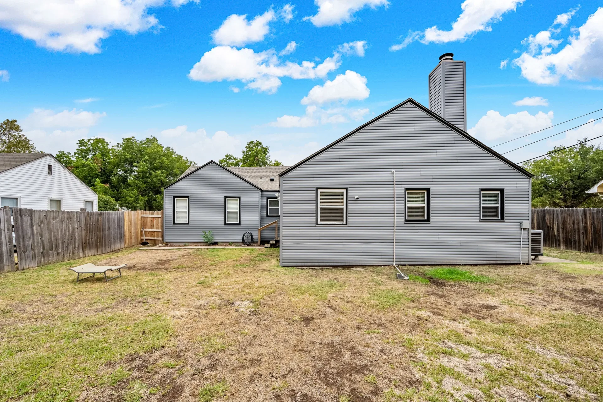 Rear view of the home showing the backyard and wood privacy fencing