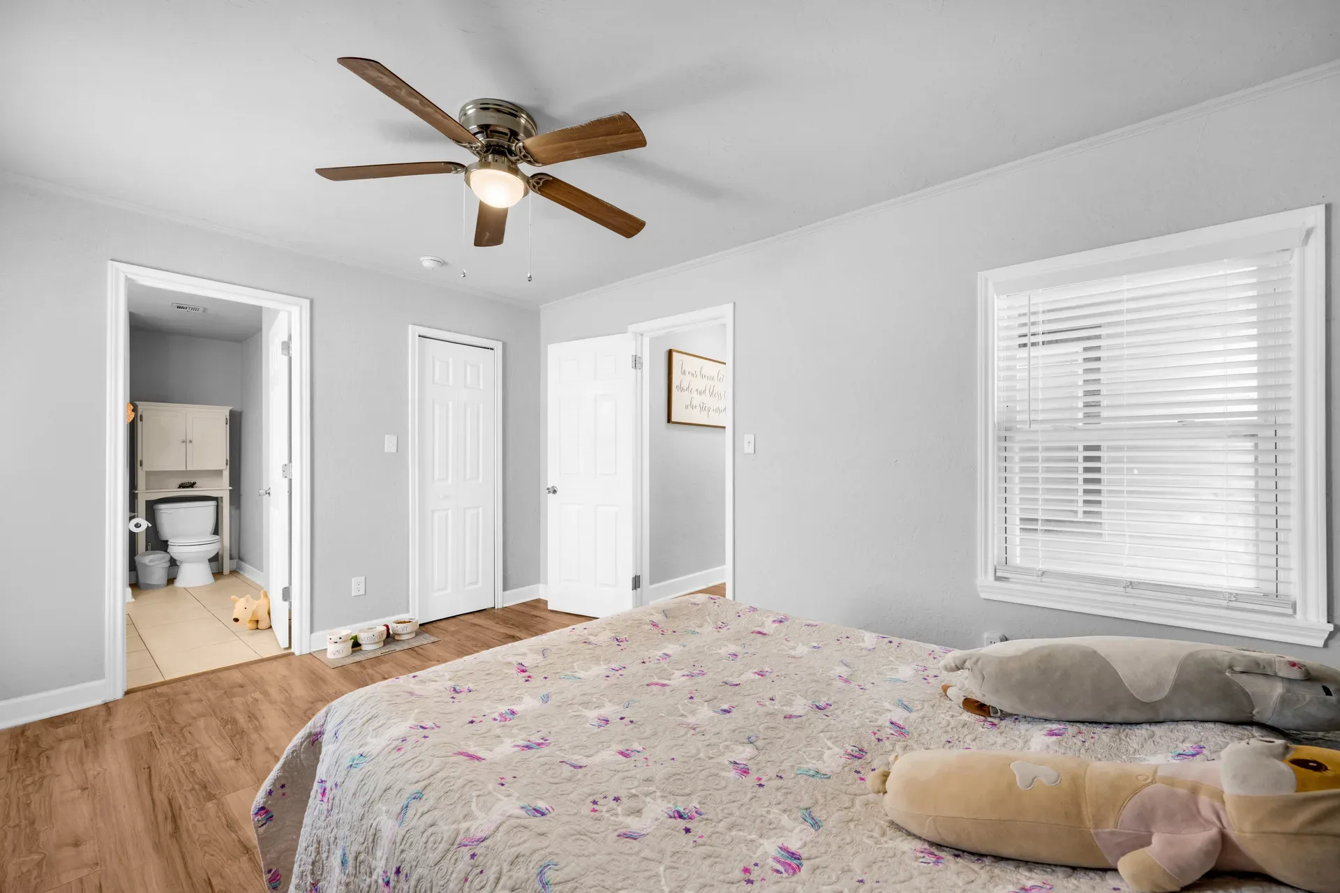 Primary bedroom with light grey walls and wood-look flooring