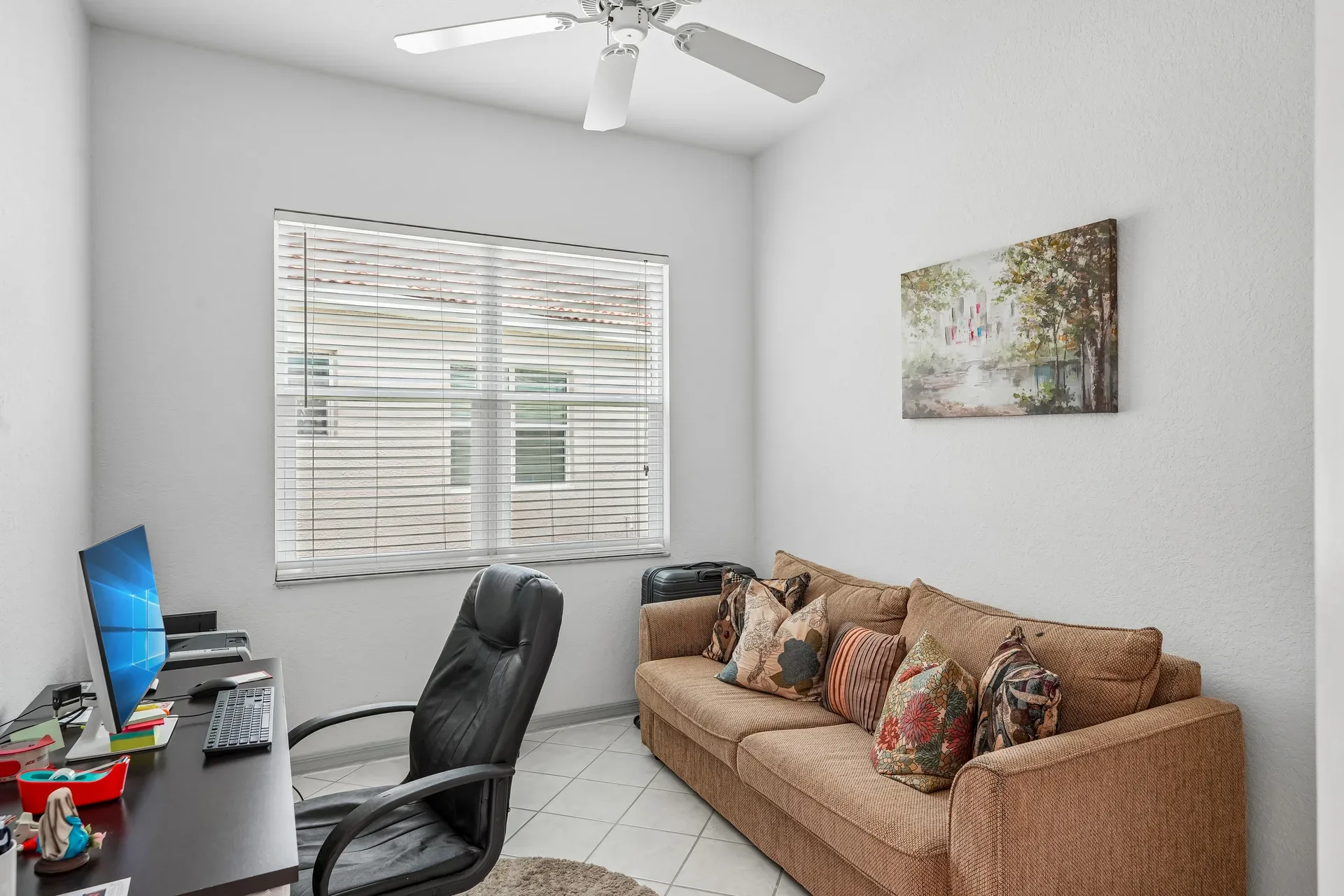 Den or home office with neutral walls and natural light through window blinds