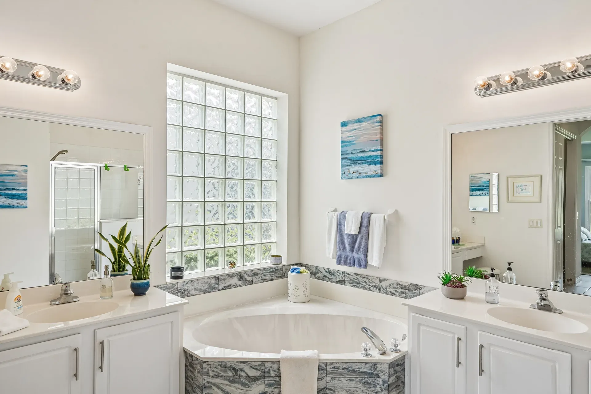 Primary bathroom with corner soaking tub, double vanity, and glass block window