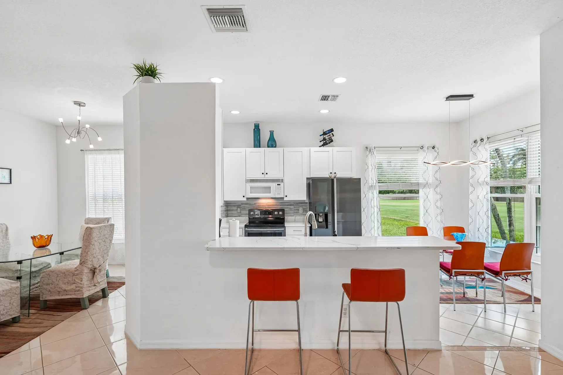 Updated kitchen and dining area with white cabinetry, quartz counters, and stainless steel appliances
