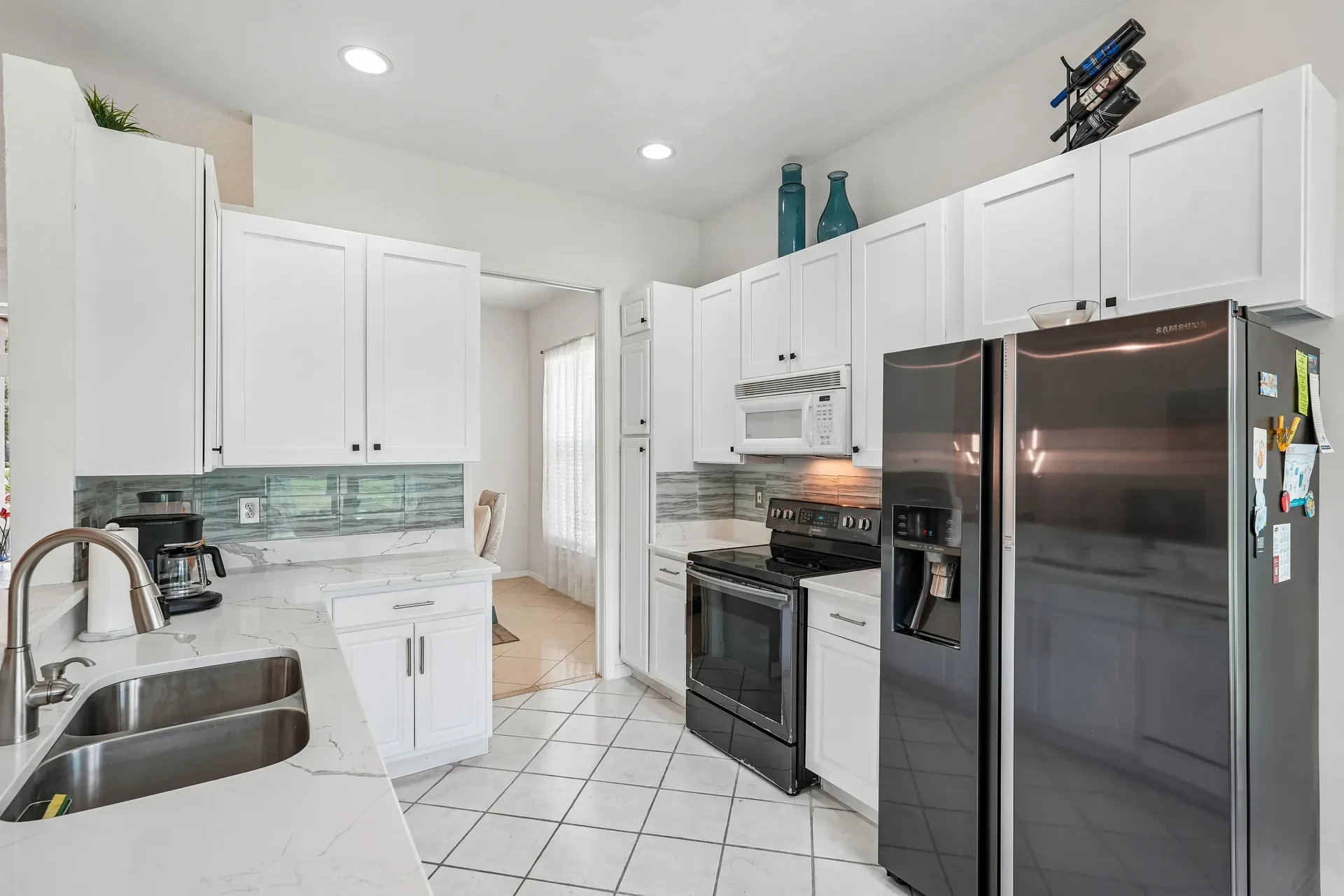 Updated kitchen with quartz countertops, white shaker cabinets, and tile backsplash