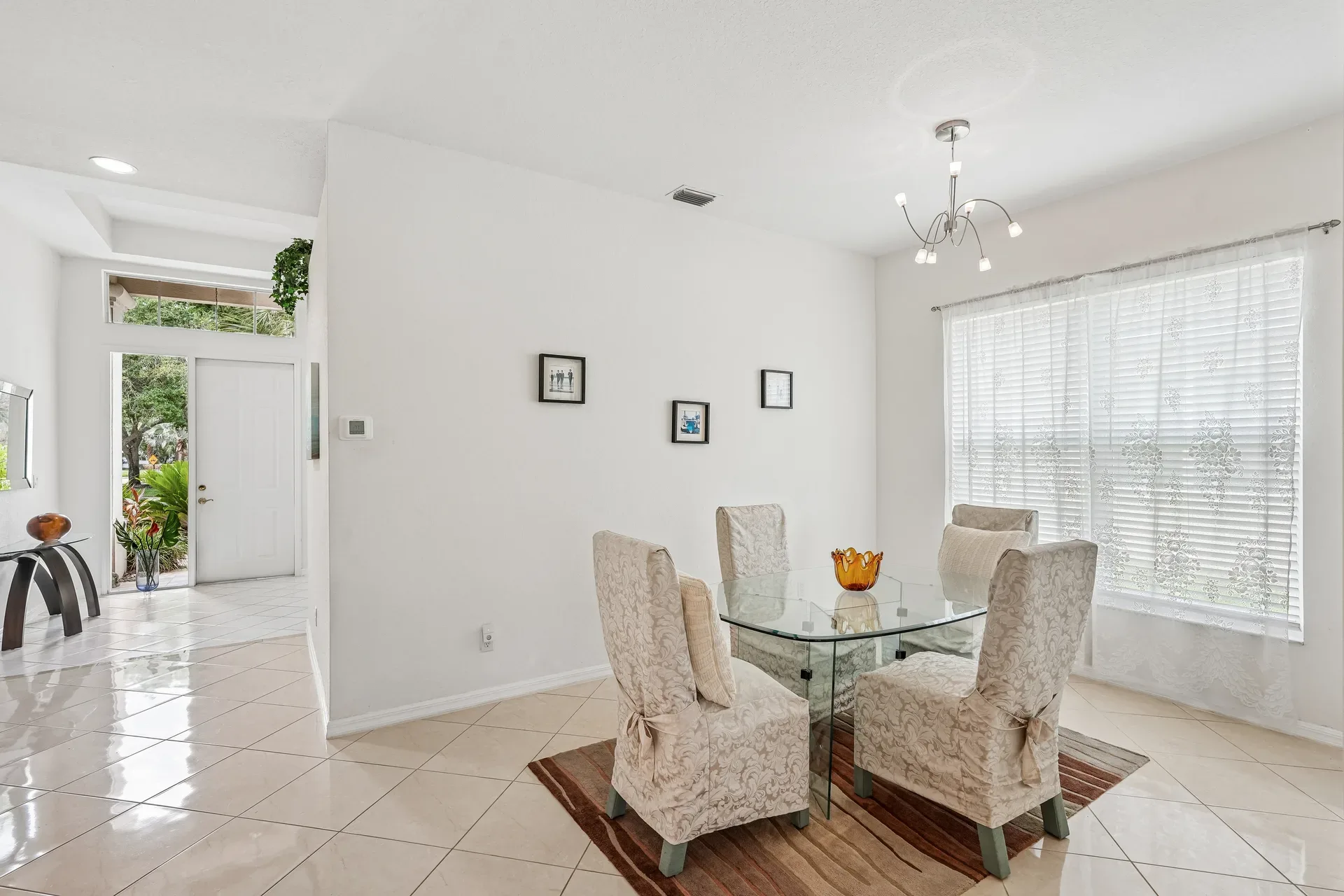 Dining room with entryway beyond, open floor plan, and tile flooring