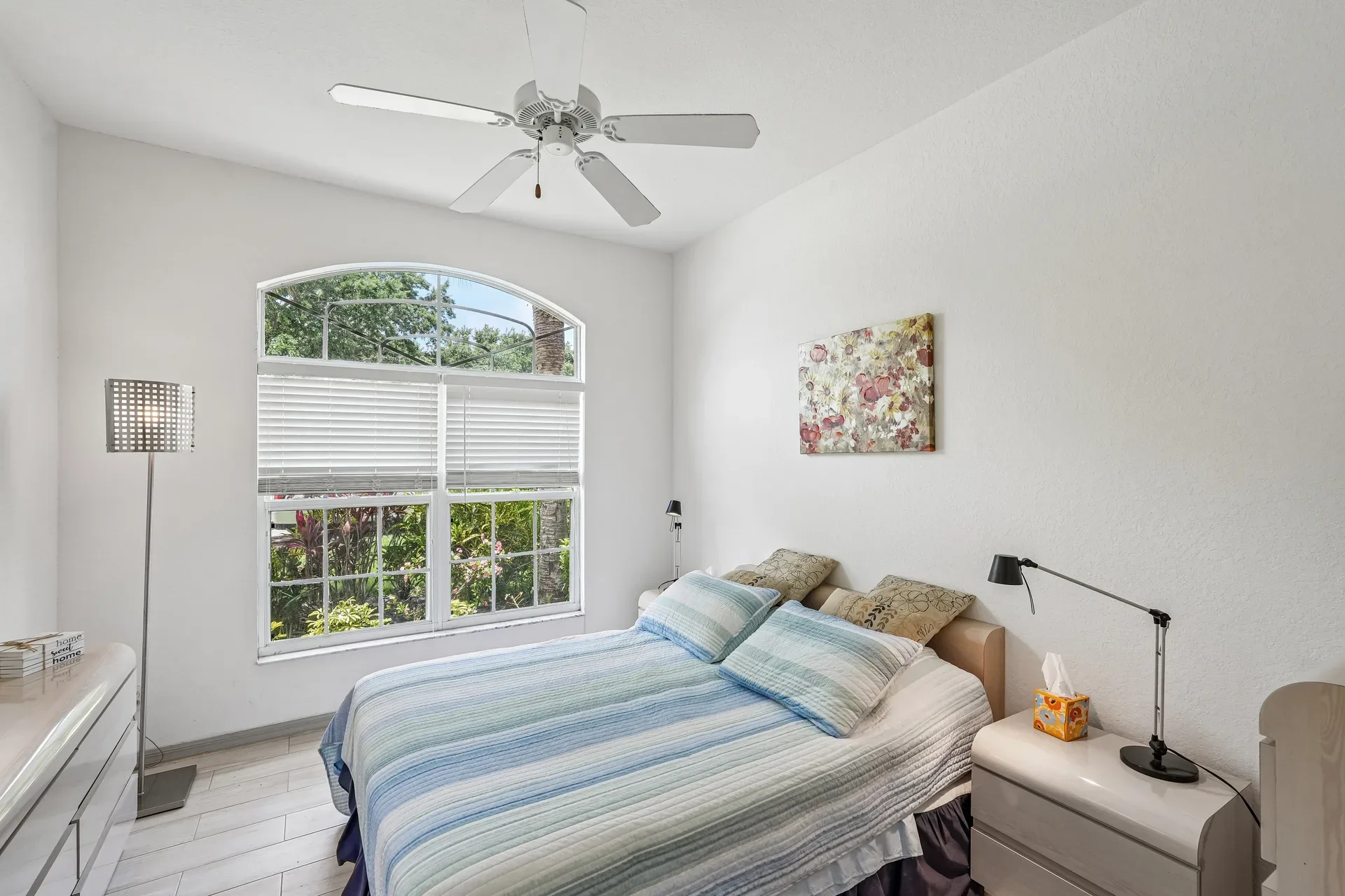 Guest bedroom with large arched window and bright natural daylight