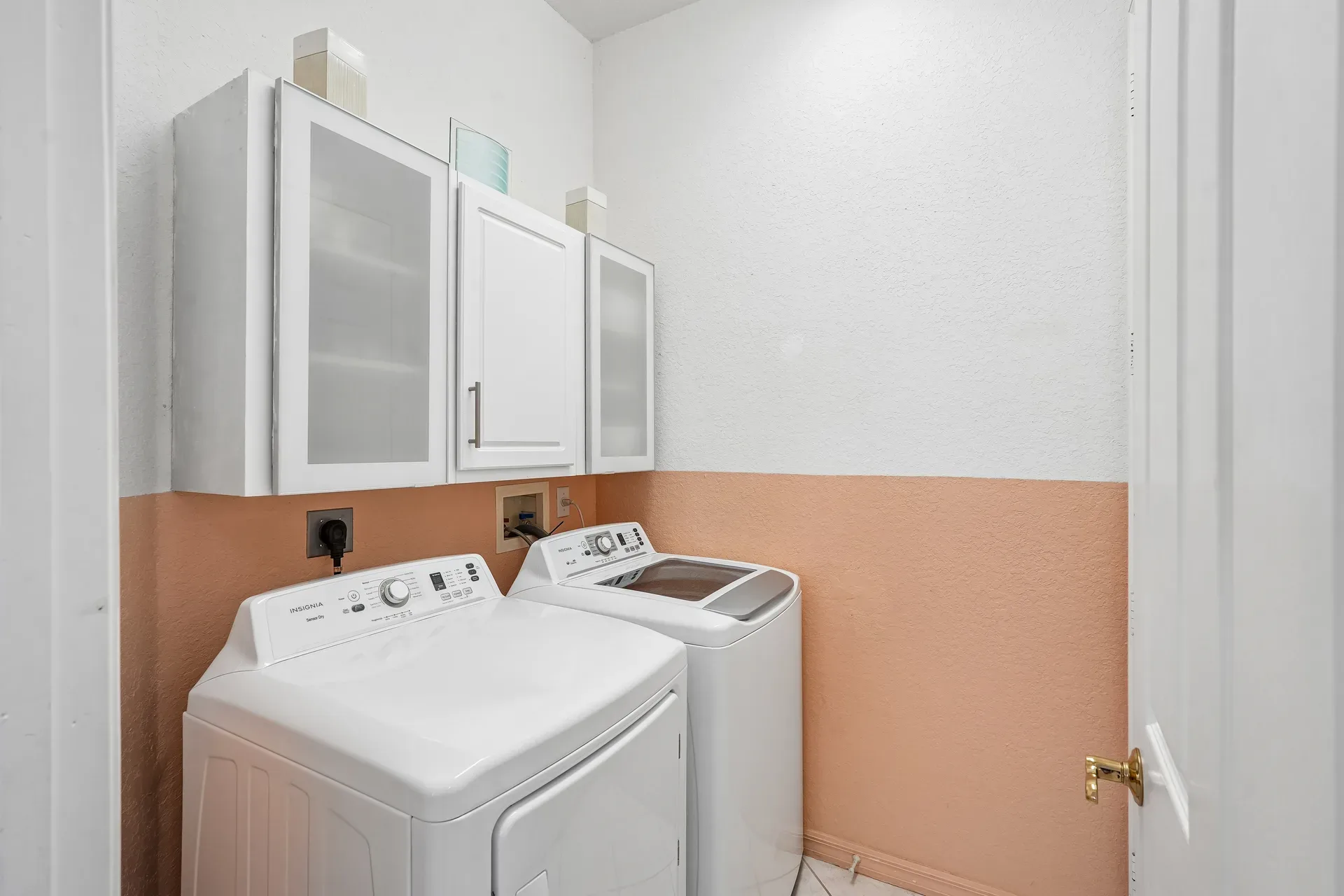 Laundry room with washer, dryer, and white upper cabinets