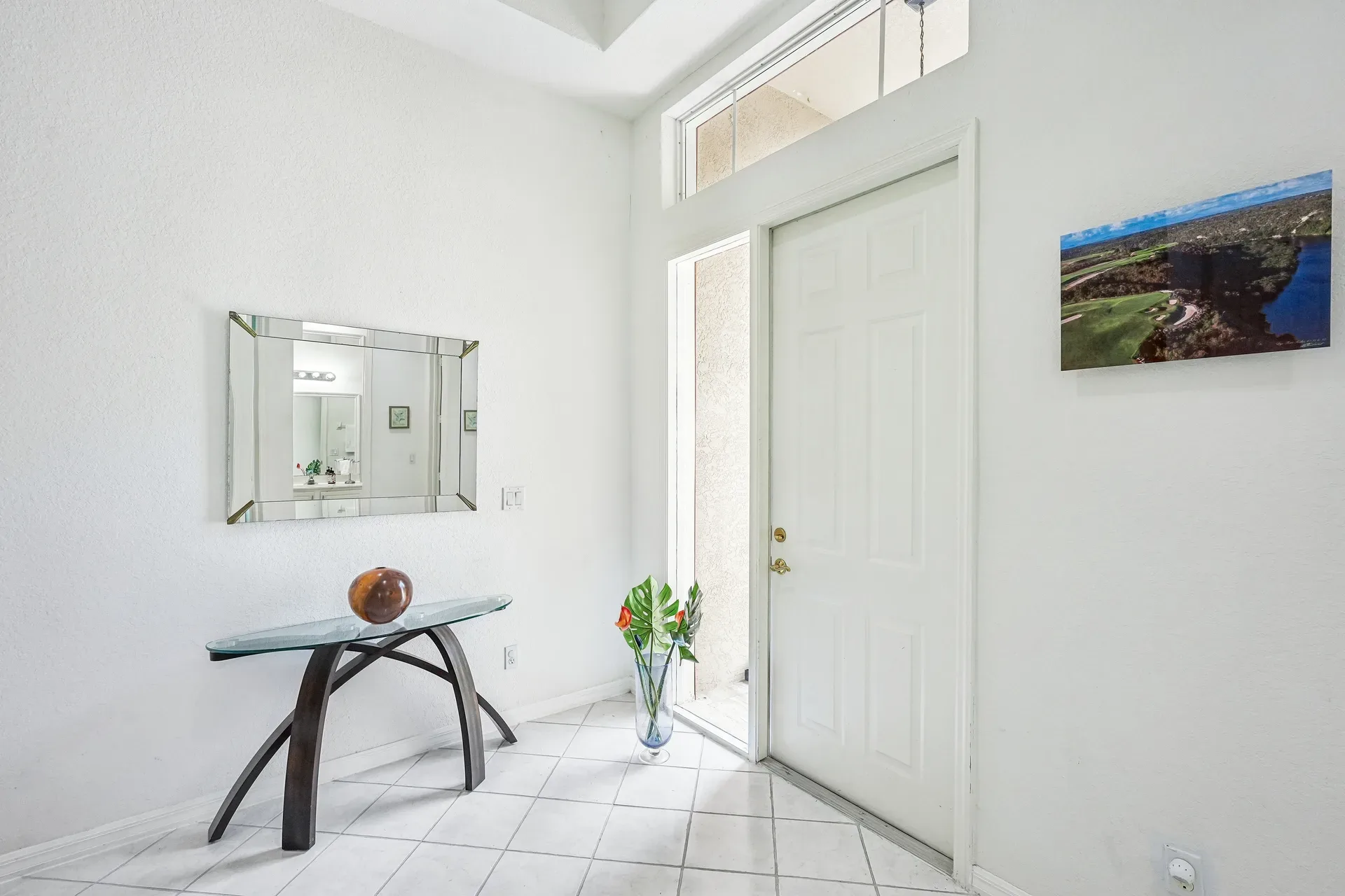 Entry foyer with white tile flooring, transom window, and bright natural daylight