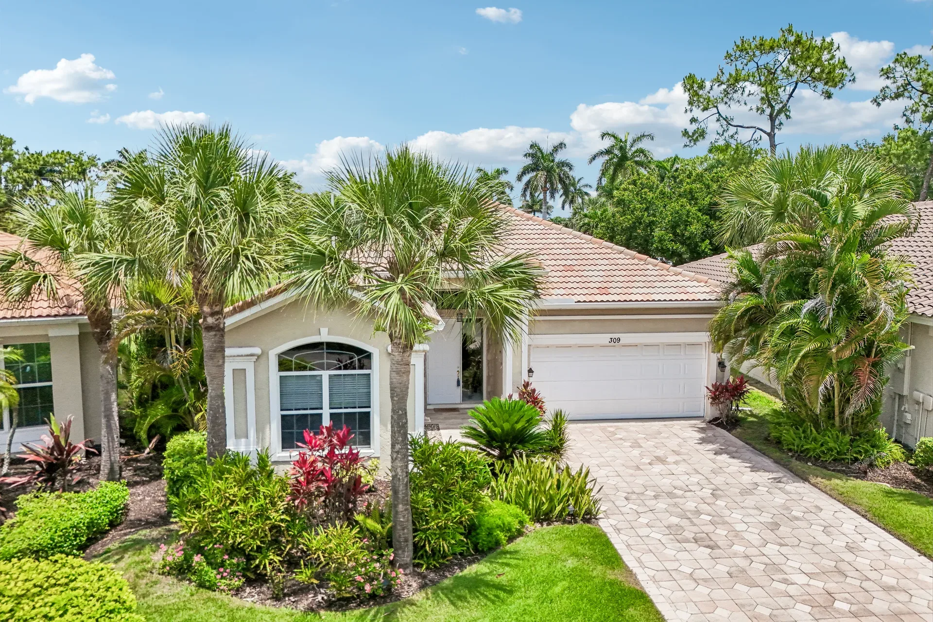 Front exterior of 309 Harvard LN with tan stucco, tile roof, and paver driveway
