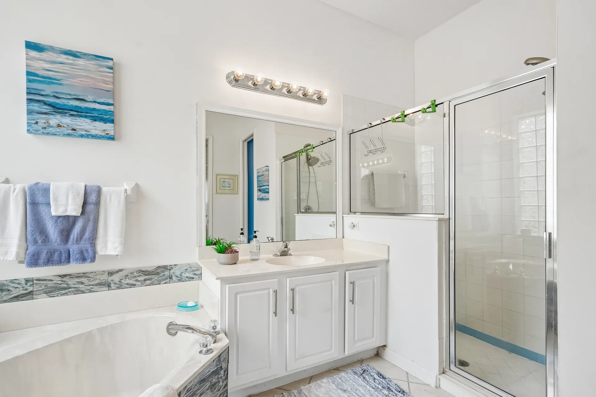 Bathroom with white vanity, soaking tub, and glass-enclosed shower