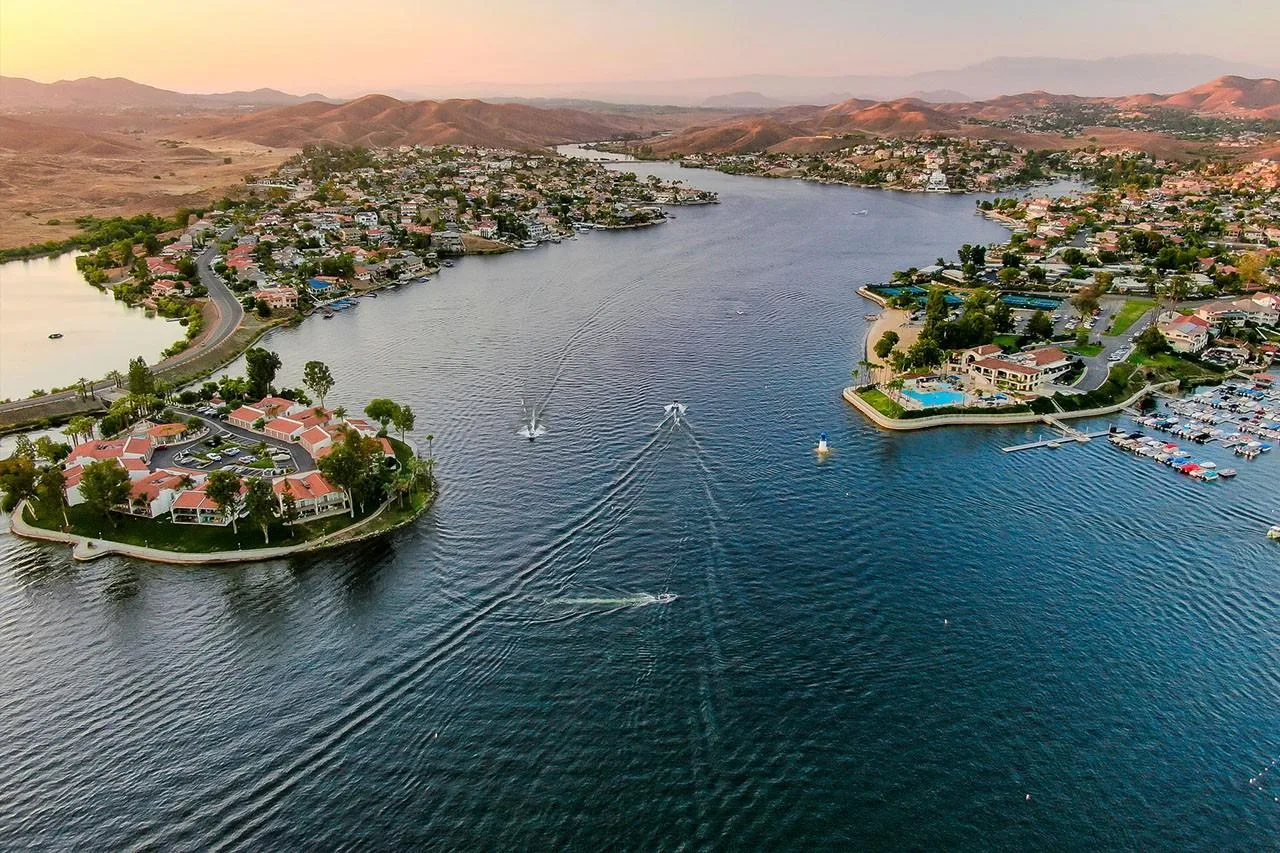 A golden-hour aerial view of the Canyon Lake community with Mediterranean-style homes and boats on the water