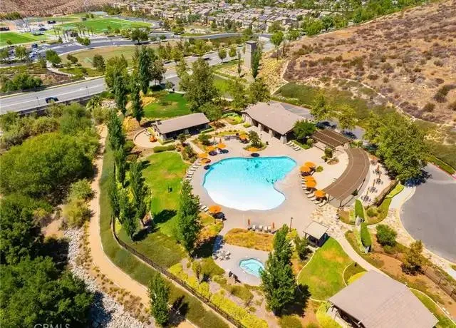 Aerial view of a community pool facility with a patio, umbrellas and a spa in the Canyon Hills area