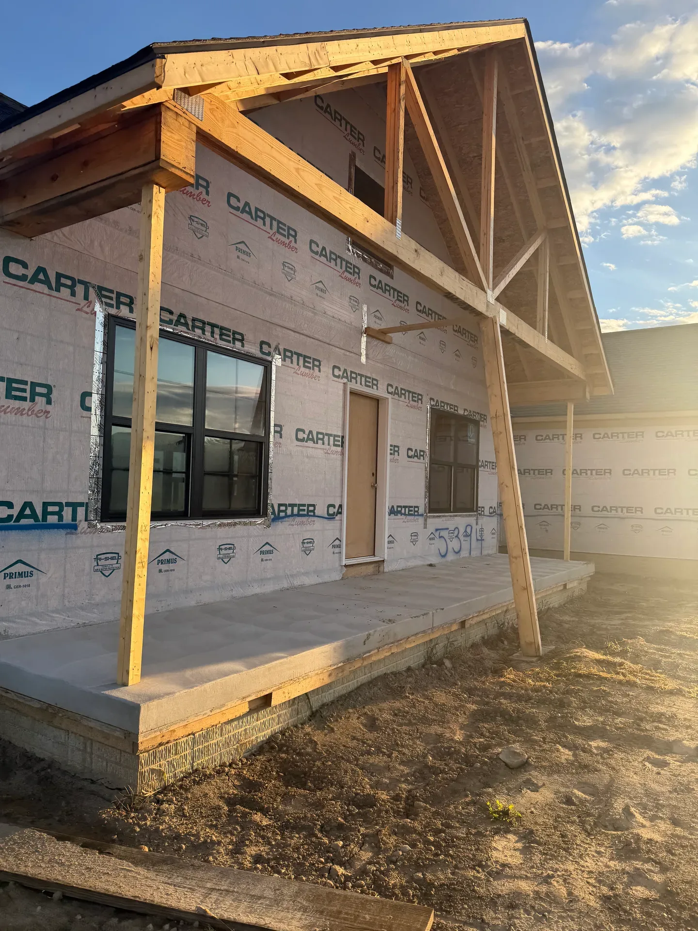 Spec home framing with exposed timber and concrete porch base