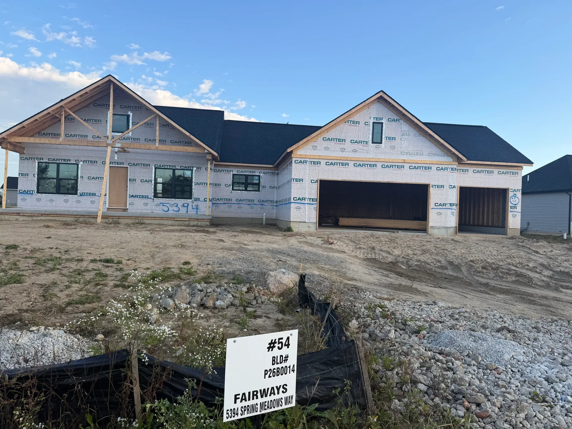 New construction framing with black window frames and dark shingle roof